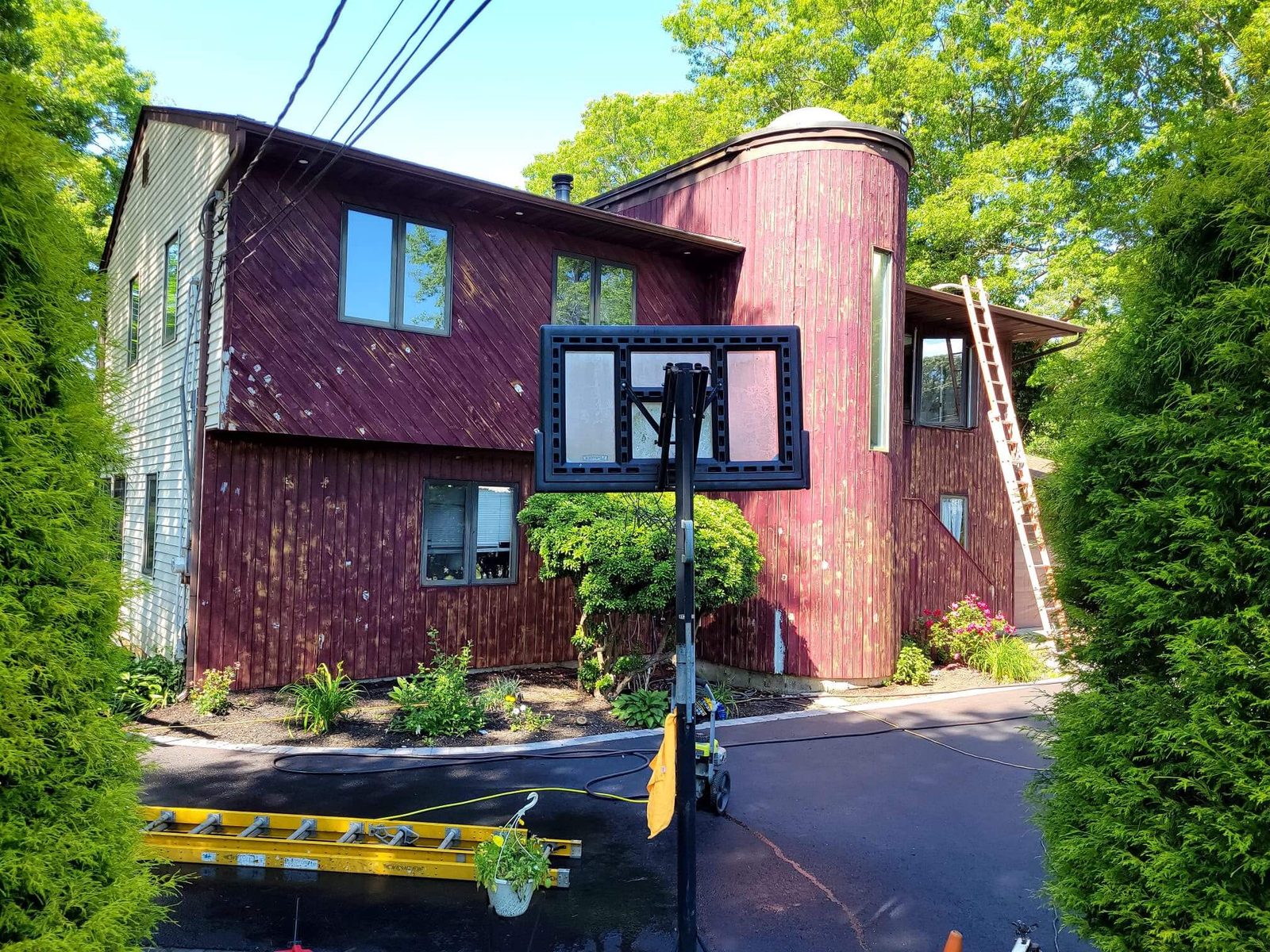 Before: two-story home with worn, faded reddish-brown vertical siding