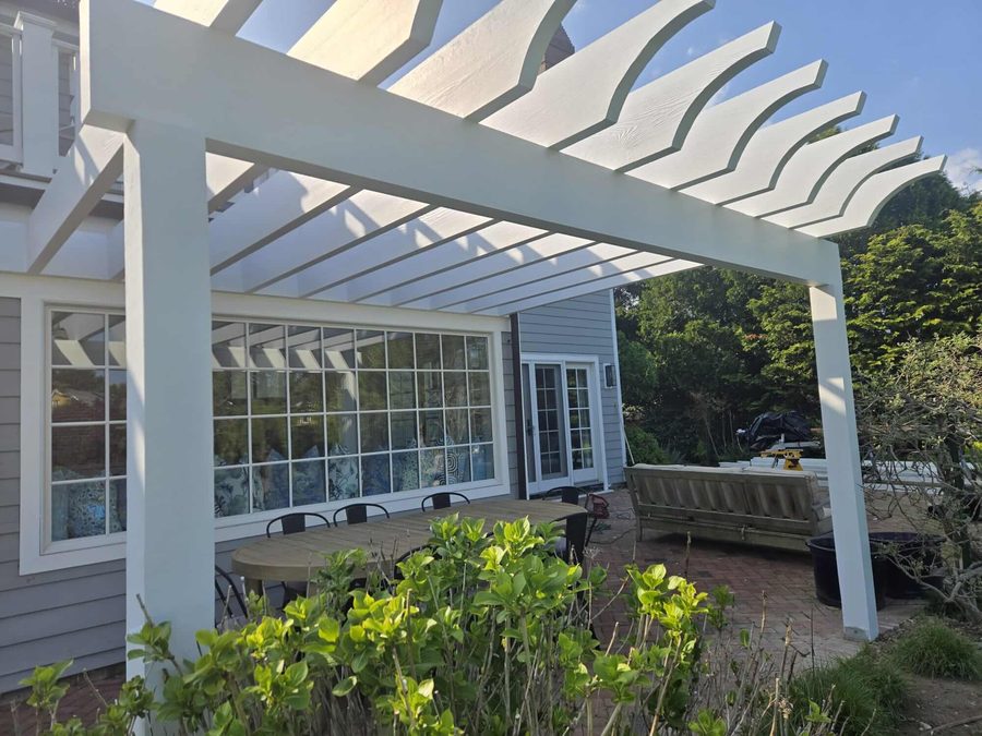 Freshly painted white pergola against a gray painted home exterior