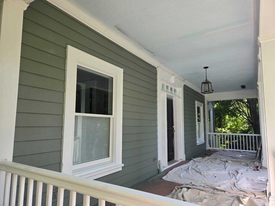 Close-up of a freshly painted porch with sage green siding and white trim detail