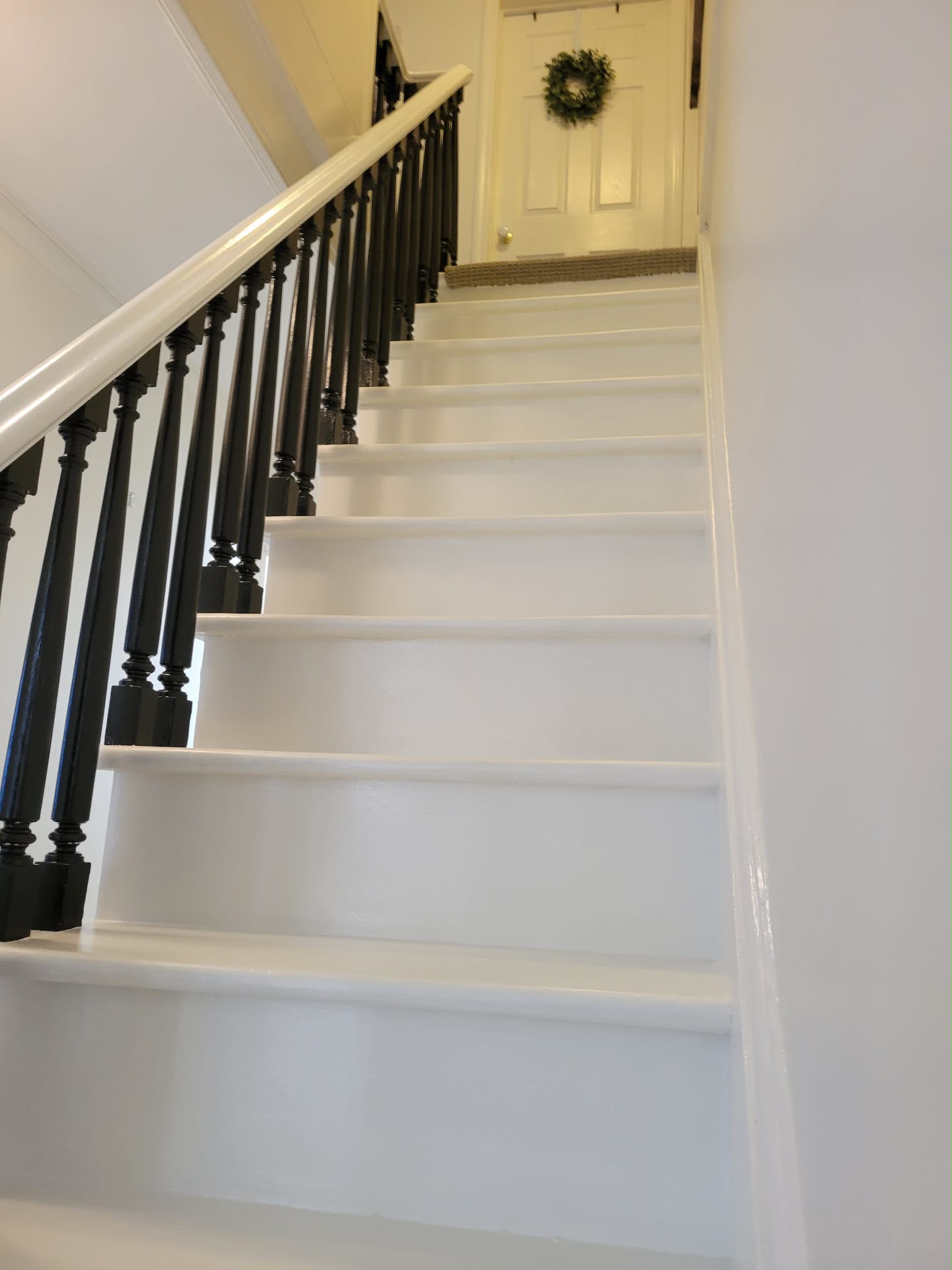 After: the same staircase freshly painted crisp white with elegant black balusters