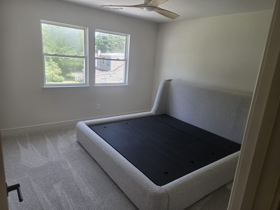 Freshly painted bedroom in soft white with new carpet and upholstered bed frame