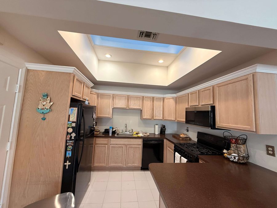 Freshly painted kitchen with light wood cabinetry and skylight